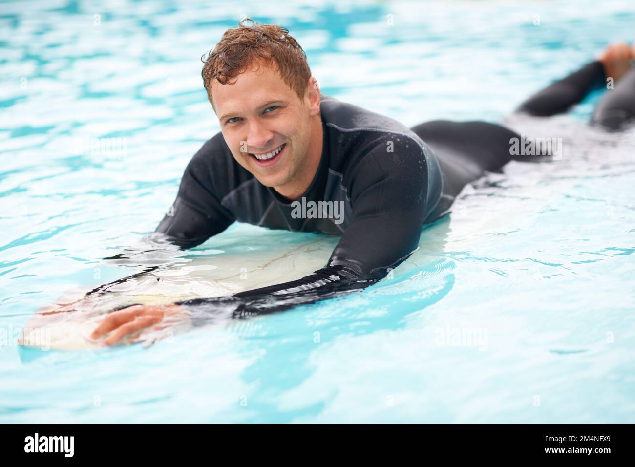 L'océan est mon terrain de jeu. un beau jeune homme qui profite d'un surf dans l'eau bleue claire. Banque D'Images