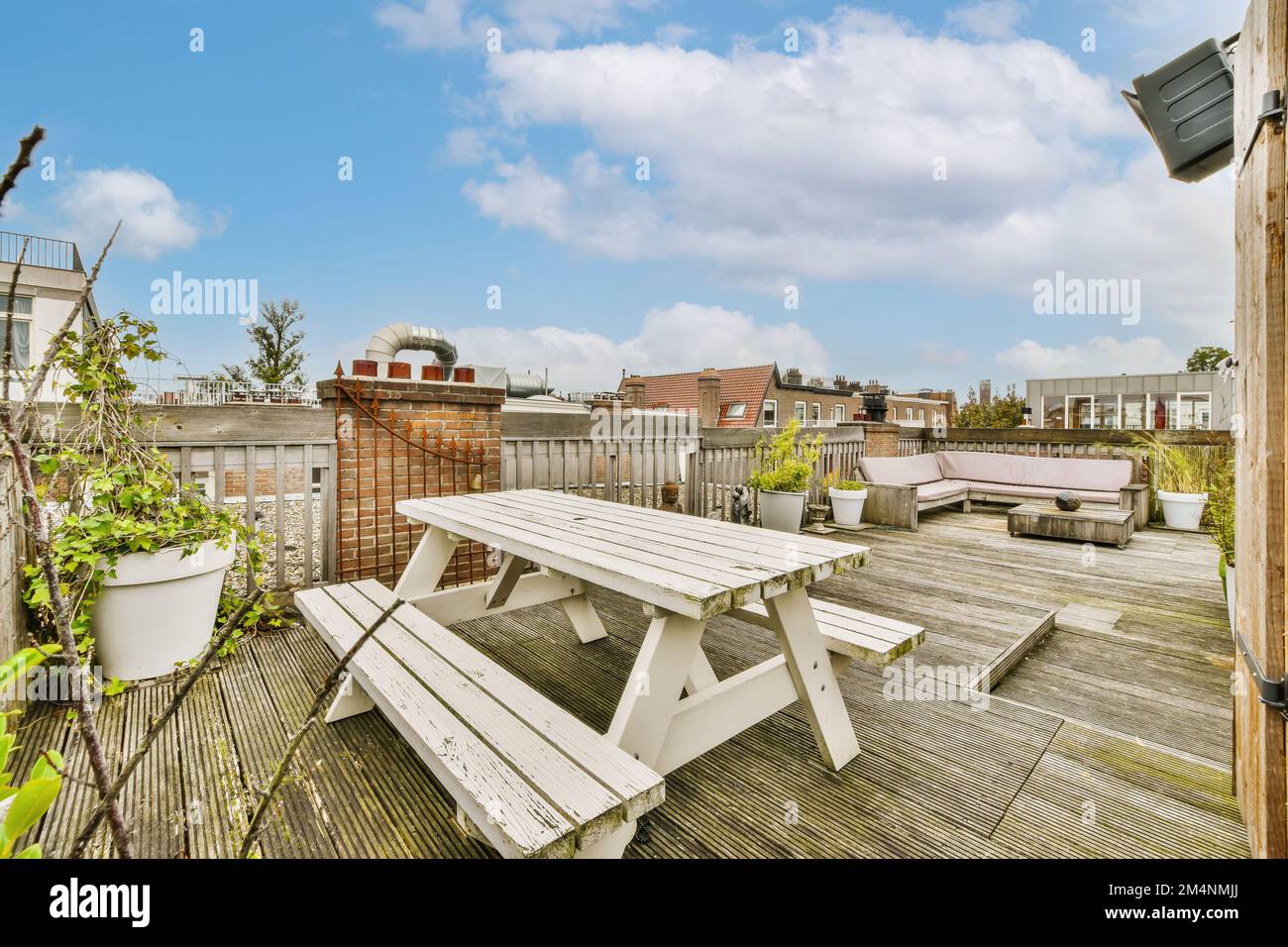 une zone extérieure avec terrasse en bois et tables de pique-nique blanches sur la photo est prise du toit à l'arrière-cour Banque D'Images