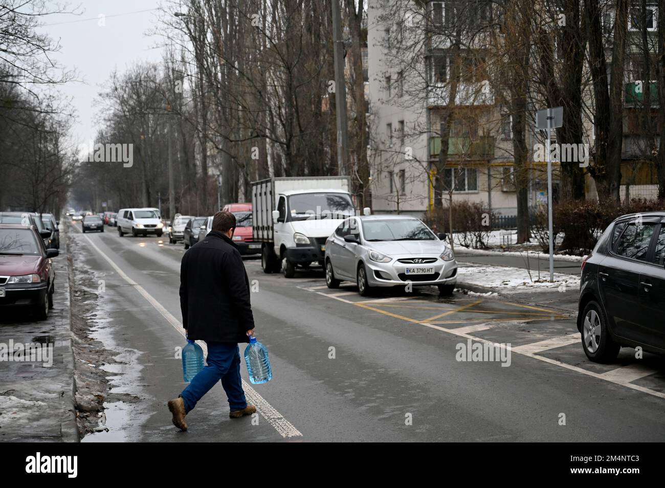 Kiev, Ukraine. 22nd décembre 2022. Un homme porte des bouteilles d'eau en plastique lors d'une panne de courant à Kiev. L'armée russe a mené des attaques massives de roquettes et de drones kamikaze sur les infrastructures énergétiques ukrainiennes. Après de graves dommages au réseau électrique dans de nombreuses villes d'Ukraine, la compagnie nationale d'électricité Ukrenergo a introduit des coupures d'électricité d'urgence et toutes les heures. (Photo par Sergei Chuzavkov/SOPA Images/Sipa USA) crédit: SIPA USA/Alay Live News Banque D'Images