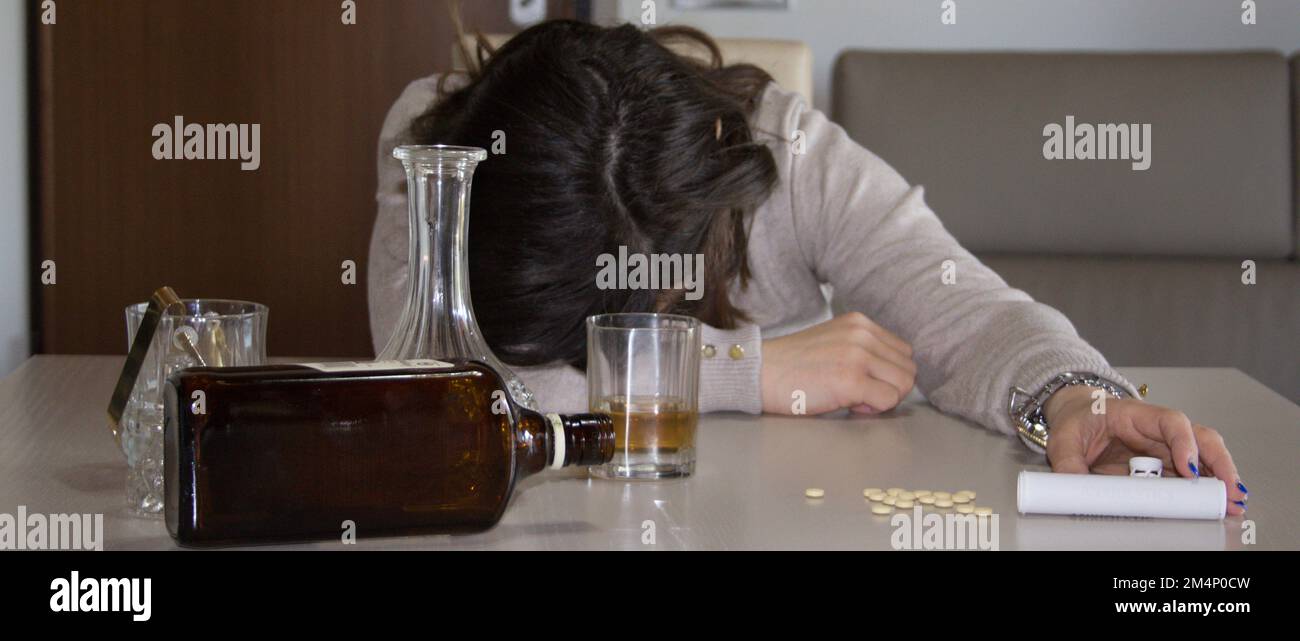 L'image d'une jeune femme est passée sur la table après avoir consommé de l'alcool et des psychotropes. Référence à l'abus et à la dépendance de ces substances Banque D'Images