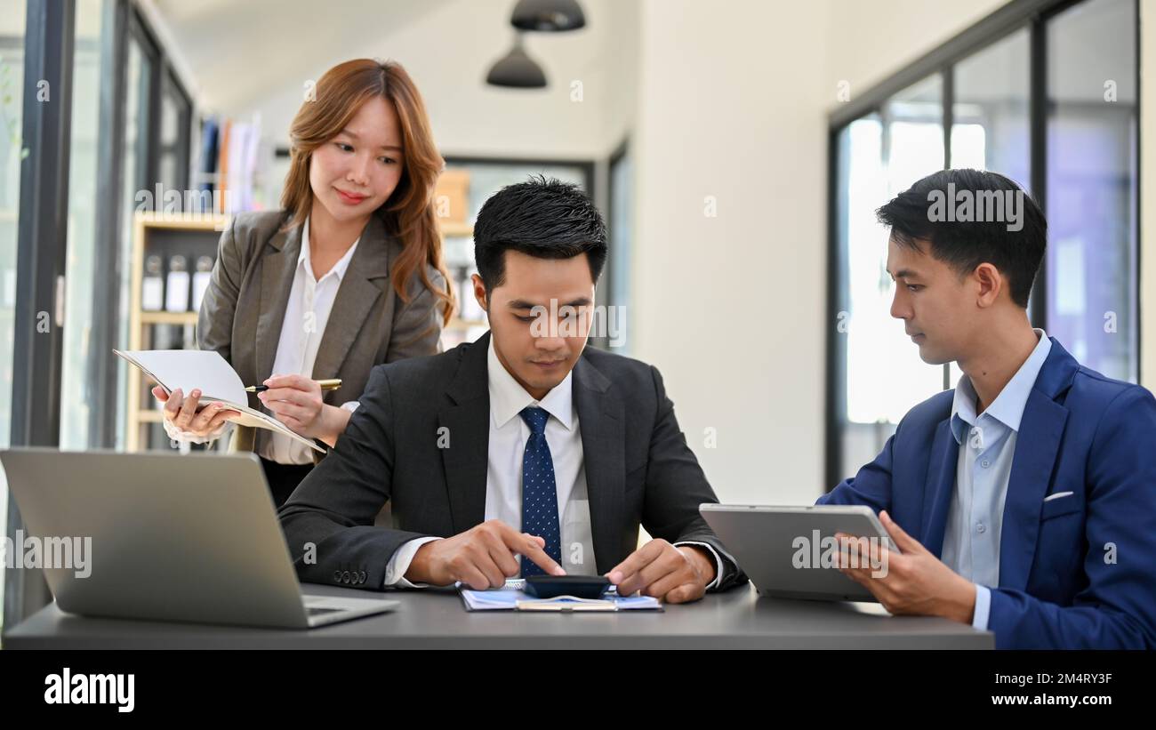 Homme d'affaires ou directeur général asiatique ciblé et intelligent qui vérifie le rapport final, en collaboration avec son équipe au bureau. les gens d'affaires s'accordent Banque D'Images