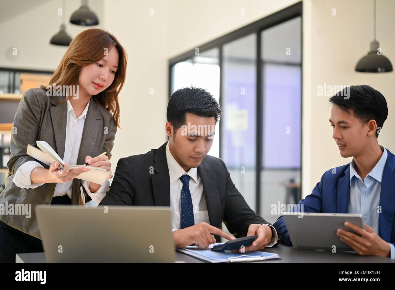 Une équipe d'analystes financiers asiatiques intelligents et professionnels ou d'hommes d'affaires remue-méninges, discutant des plans et travaillant ensemble au bureau. Banque D'Images