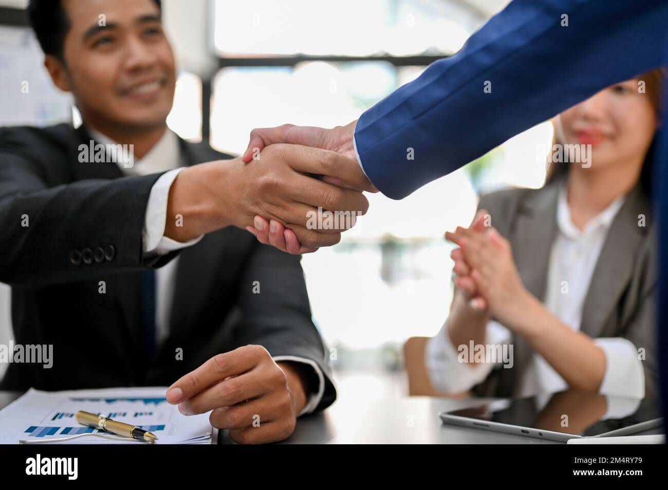 Un homme d'affaires ou un directeur exécutif asiatique professionnel et prospère du millénaire qui se fait la main avec son partenaire d'affaires après la réunion. félicitations Banque D'Images