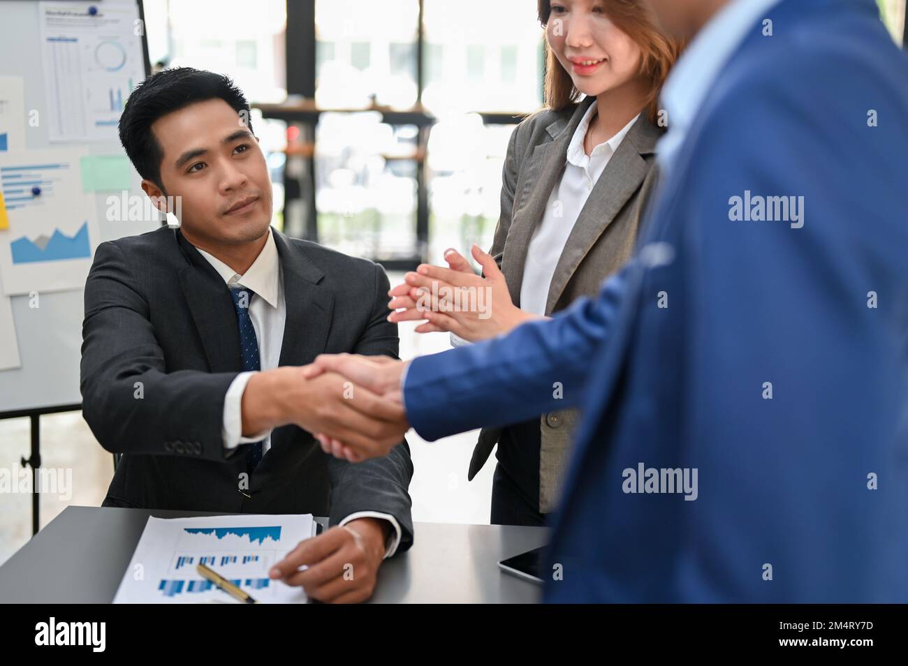 Un homme d'affaires ou un directeur exécutif asiatique professionnel et prospère du millénaire qui se fait la main avec son partenaire d'affaires après la réunion. Banque D'Images