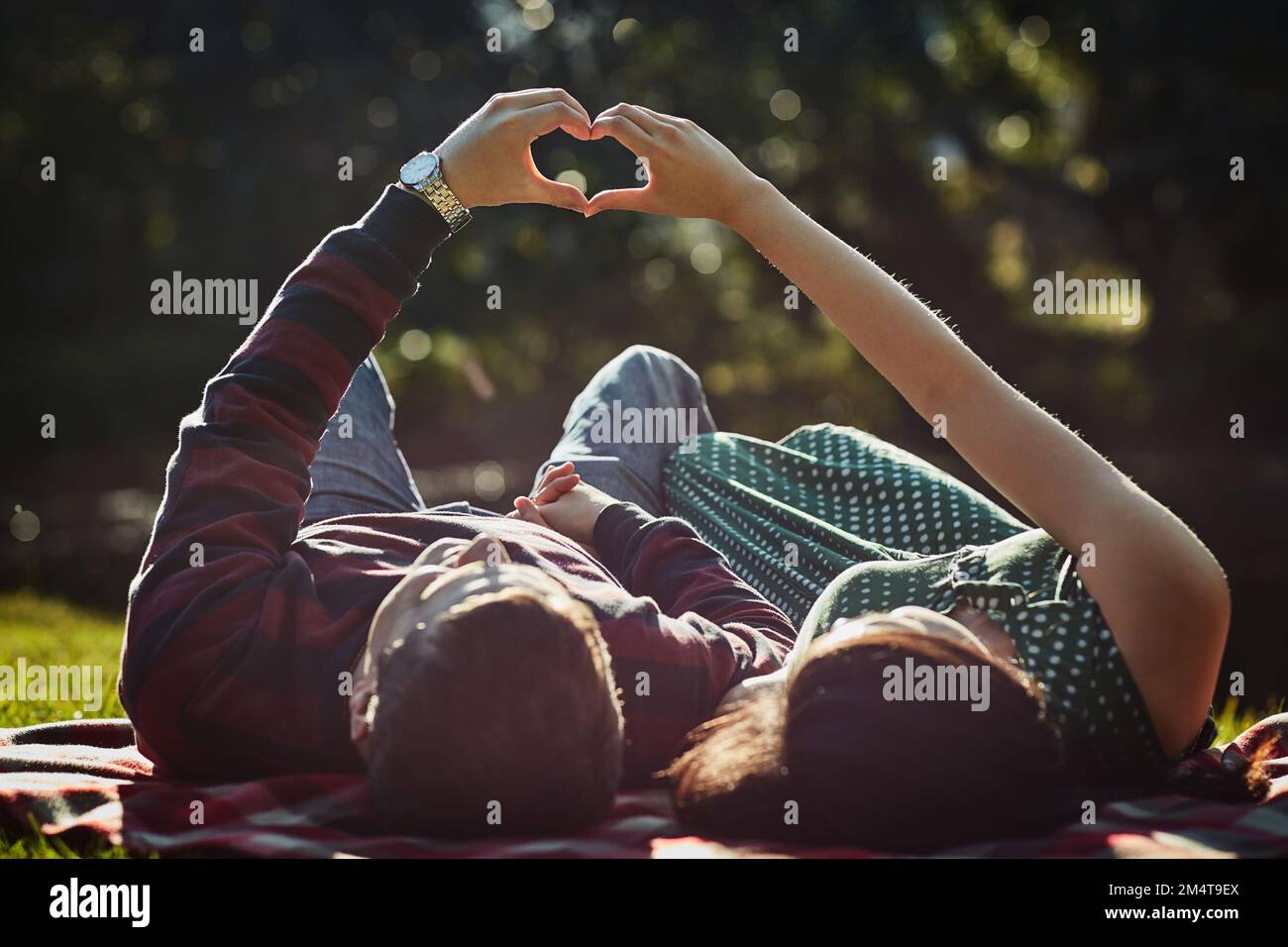 L'amour vrai est tout. un jeune couple allongé ensemble sur l'herbe et faisant un geste de coeur avec leurs mains. Banque D'Images