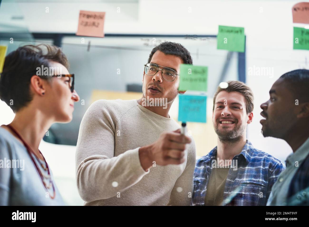 Mettre en place de grands projets. un groupe de concepteurs remue-méninges avec des notes sur un mur de verre dans un bureau. Banque D'Images