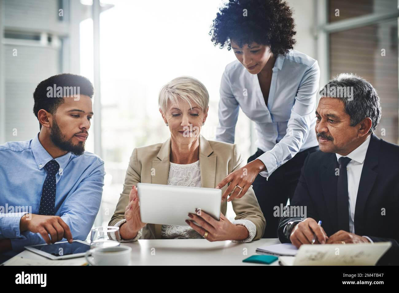 Passez au numérique et profitez des avantages. un groupe d'hommes d'affaires discutant de quelque chose sur une tablette numérique lors d'une réunion. Banque D'Images