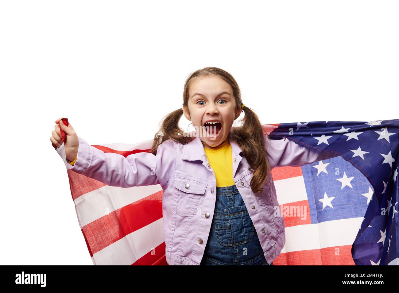 Espiègle petite fille drôle, citoyen américain porte le drapeau américain, regarde la caméra, isolée sur fond blanc. Espace publicitaire Banque D'Images