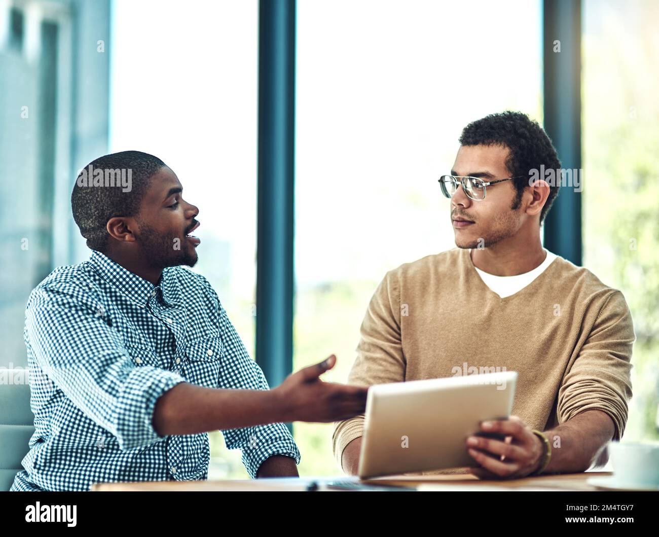 Vous pouvez désormais trouver des solutions pour vous aider dans tous les aspects de votre entreprise. deux jeunes concepteurs discutent de quelque chose sur une tablette numérique. Banque D'Images