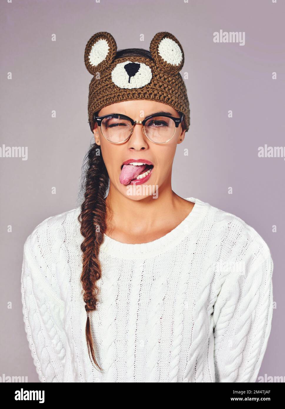 Devinez mon animal d'esprit. Photo studio d'une jeune femme portant un bonnet en forme d'ours en peluche marron. Banque D'Images