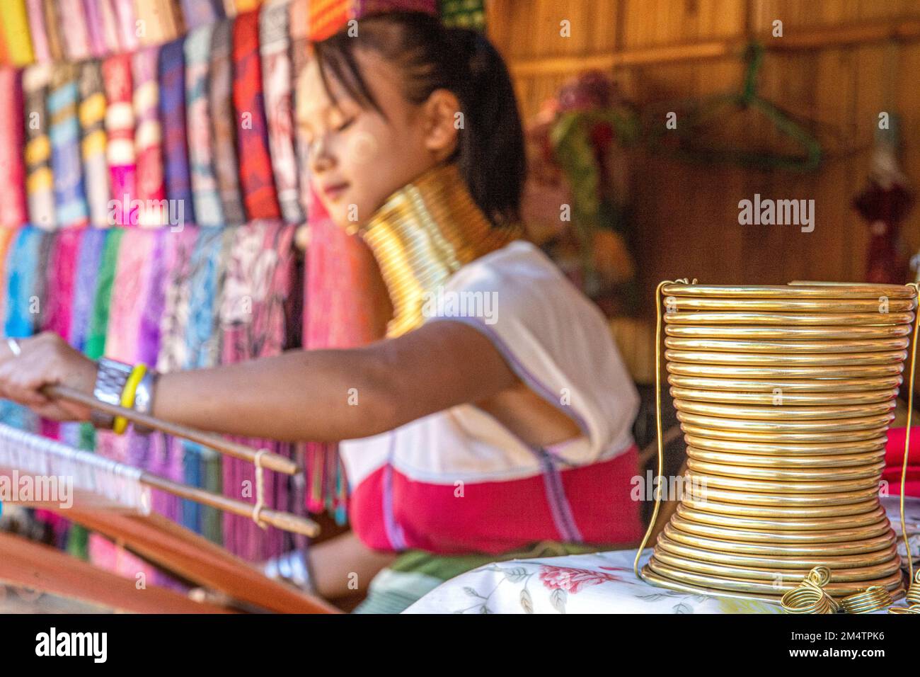 (221223) -- CHIANG RAI, le 23 décembre 2022 (Xinhua) -- Une femme déchaîne des tissus dans un village Karen de Chiang Rai, Thaïlande, le 22 décembre 2022. Le peuple Karen, qui vit dans le nord-ouest de la Thaïlande, considère les longs cols comme de la beauté. Les filles locales commencent à porter des colliers en cuivre à l'âge de 4 ou 5 ans. Avec le changement de temps, le nombre de femmes portant des colliers a considérablement diminué, et la coutume de long cou est progressivement entrée dans l'histoire. (Xinhua/Wang Teng) Banque D'Images