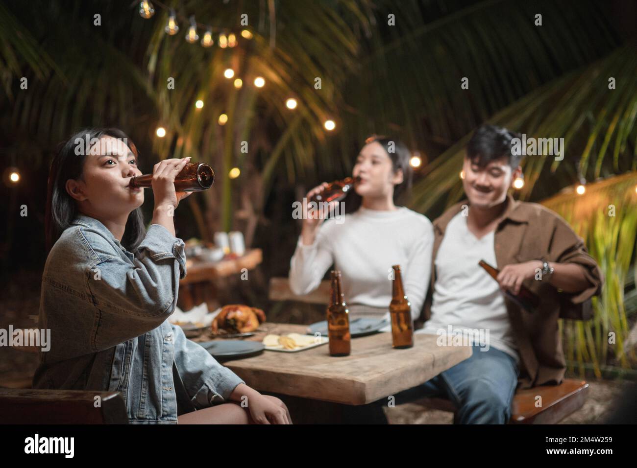 Femme tenant une bouteille de bière buvant à une fête Banque D'Images