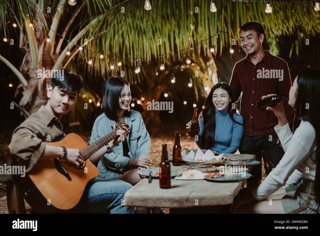 Des groupes asiatiques jouant de la guitare à la fête et buvant de la bière Banque D'Images
