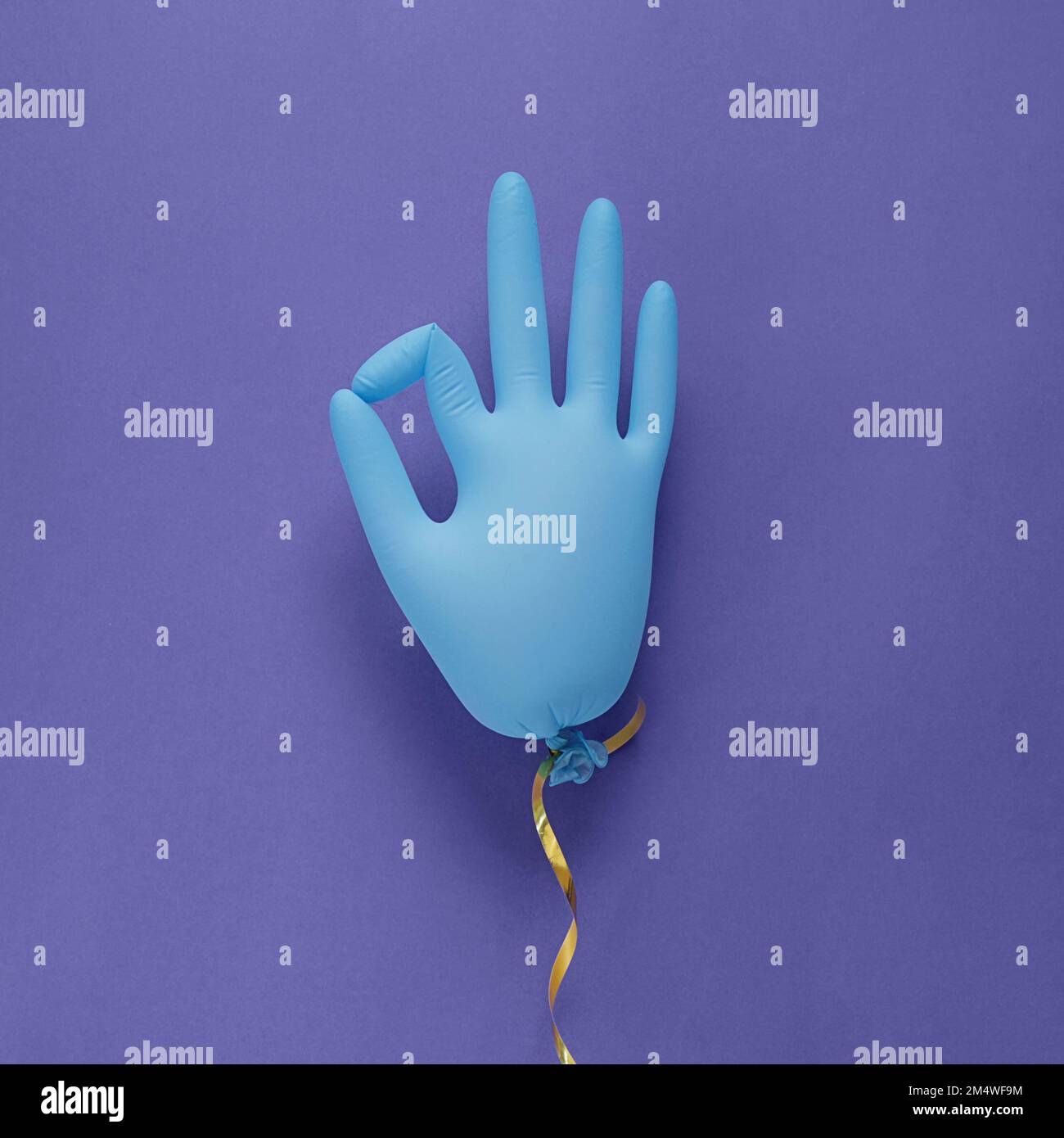 Blue latex Medical gants comme ballon sur fond violet, montre le caractère OK. Couleur très Peri - couleur de l'année 2022. Concept de minimalisme. Banque D'Images
