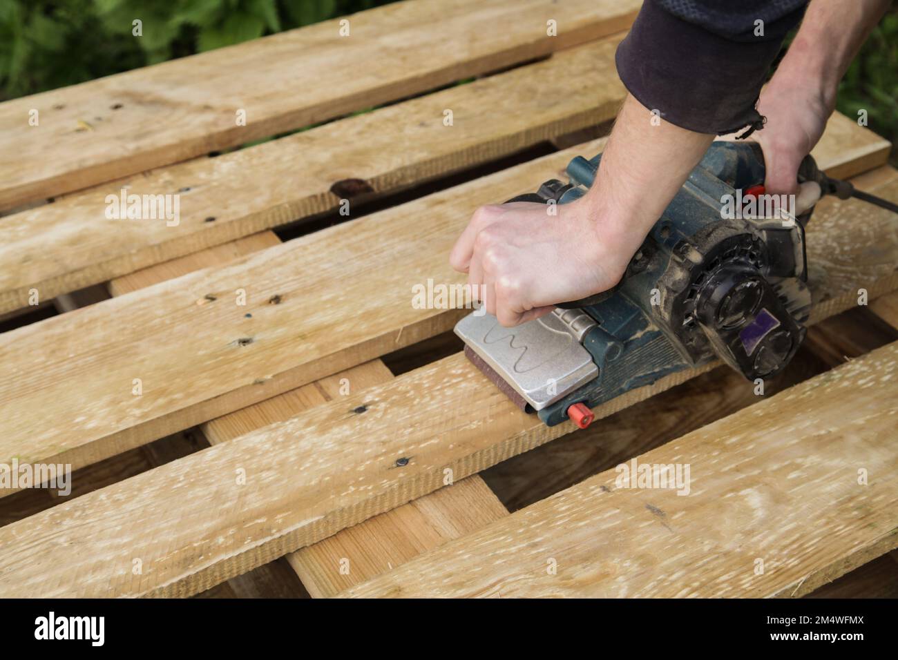 Les mains mâles traitent les planches en bois, palette avec ponceuse Photo  Stock - Alamy