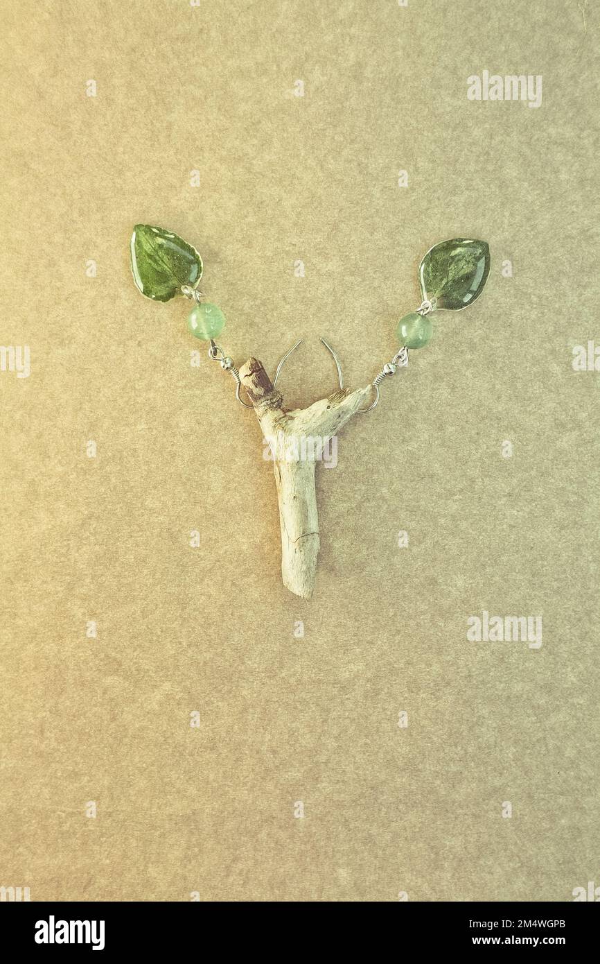 Gros plan des boucles d'oreilles originales avec des feuilles et des perles vertes photo concept Banque D'Images