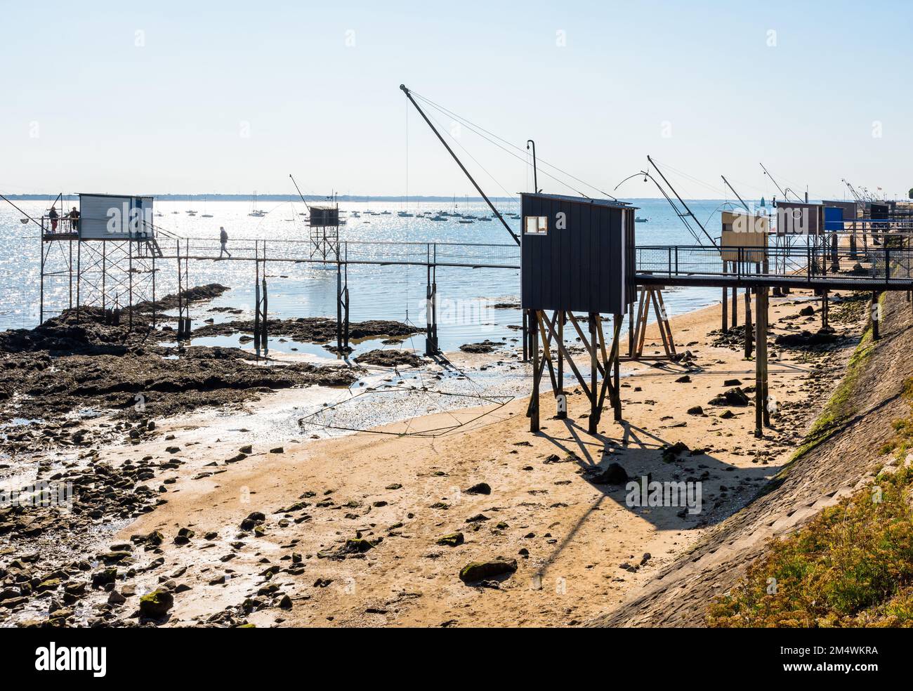 Cabines de pêche avec un grand filet de remontée mécanique carré appelé 'carrelet' aligné sur la plage de Saint-Nazaire, en France, à marée basse lors d'une journée ensoleillée d'été. Banque D'Images