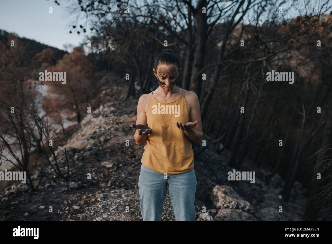 Femme regardant la main pleine de cendres dans la forêt Banque D'Images