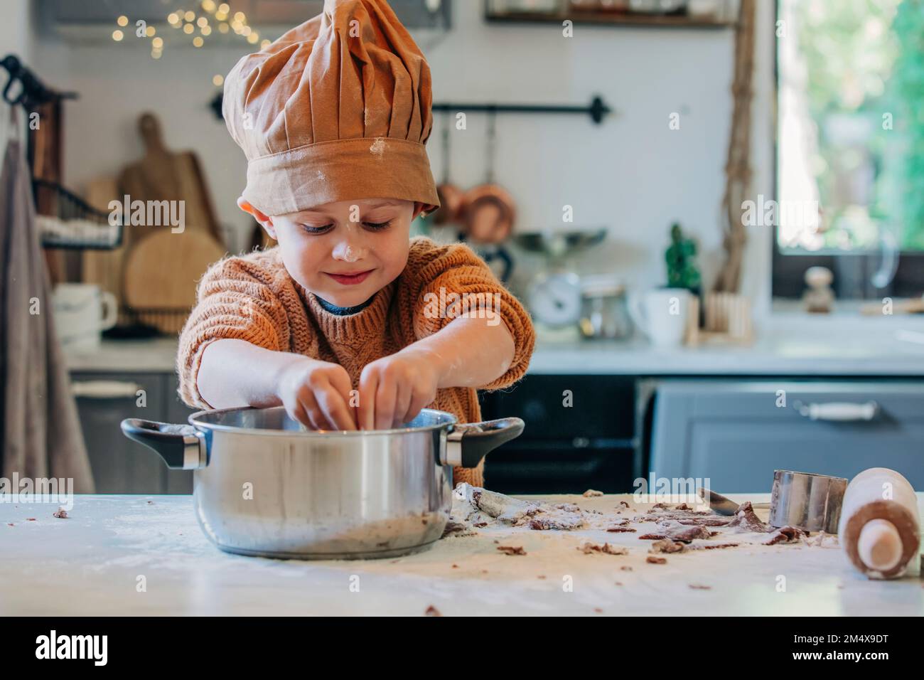 Un garçon souriant portant un chapeau de chef cuisinier préparant la  nourriture dans un ustensile à la maison Photo Stock - Alamy