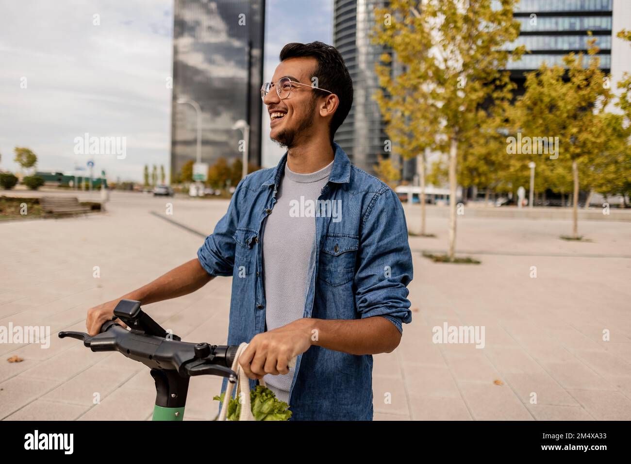 Jeune homme heureux avec un scooter électrique de poussée debout sur la piste de marche Banque D'Images