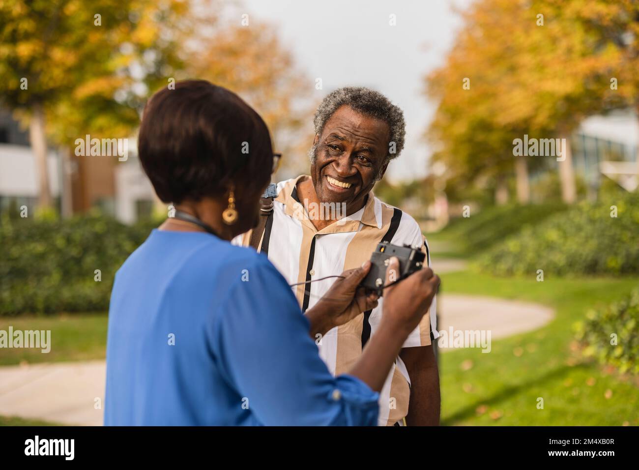 Homme heureux regardant une femme tenant la caméra dans le parc Banque D'Images