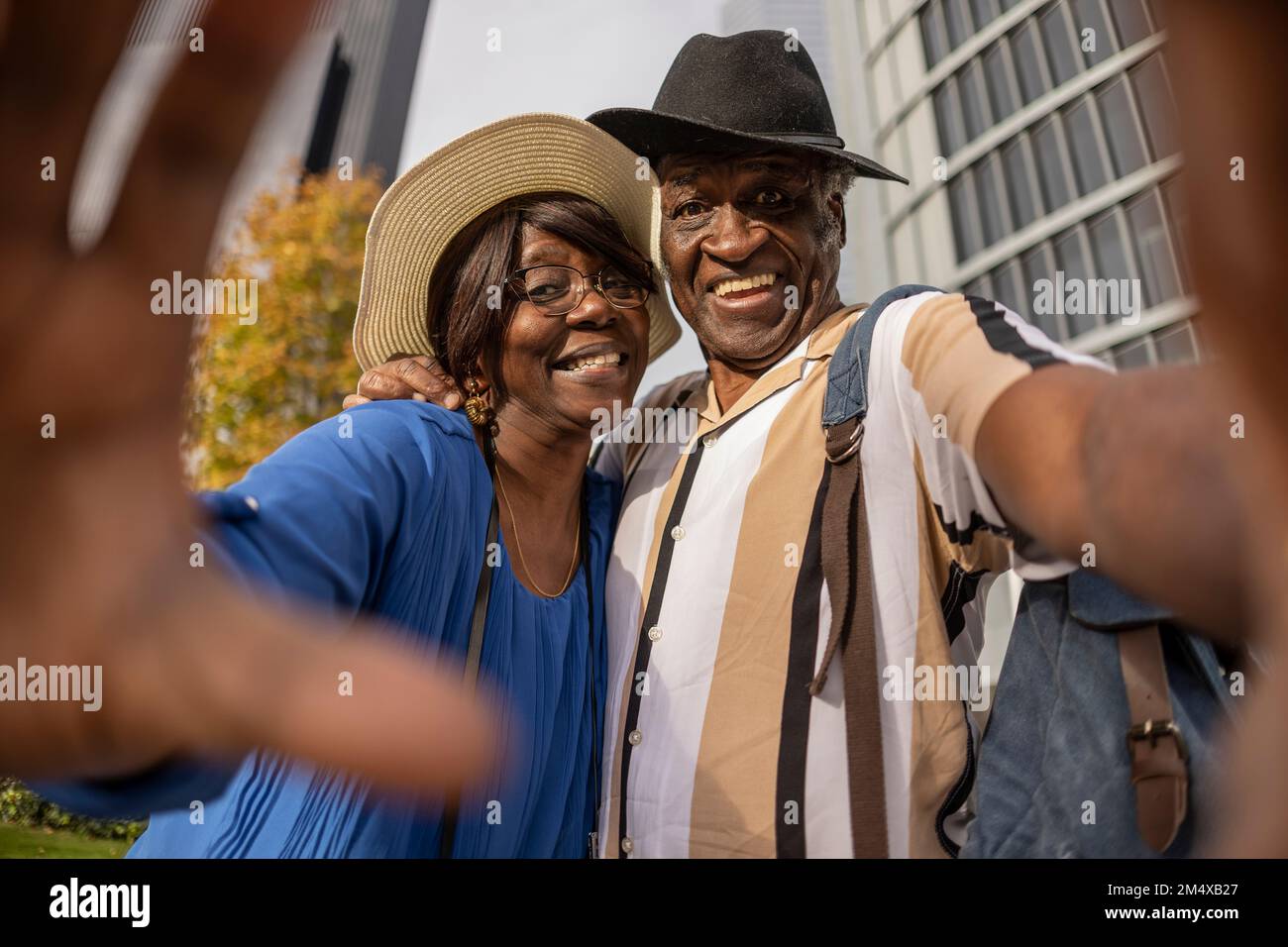 Heureux couple senior portant des chapeaux faisant des gestes au parc Banque D'Images