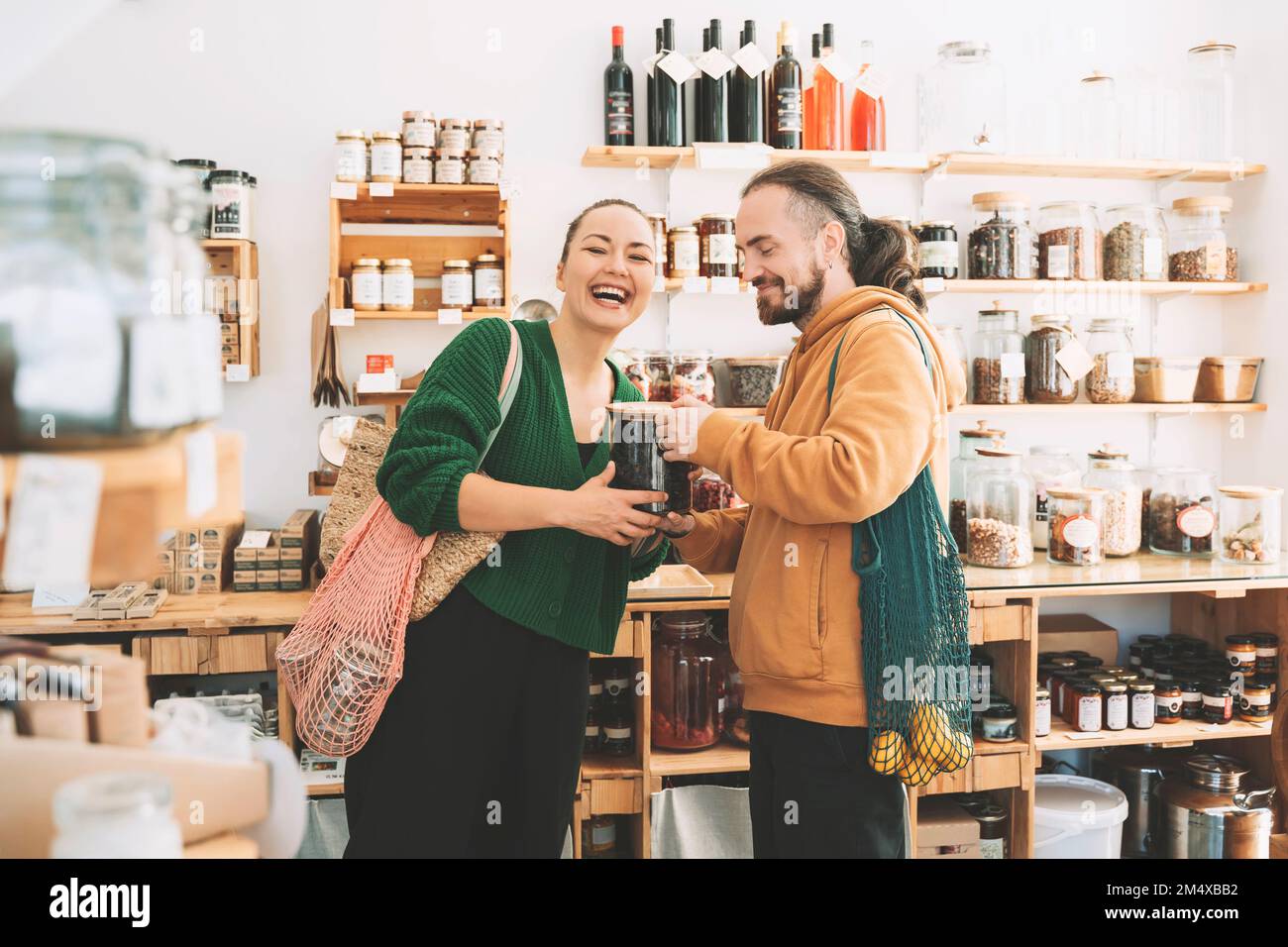 Un homme et une femme heureux avec un pot de maçon à zéro magasin de déchets Banque D'Images