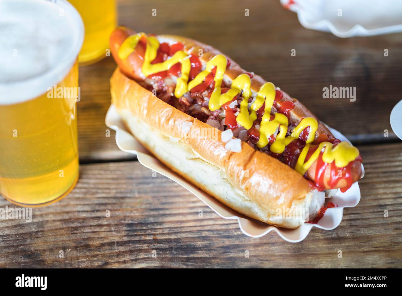 Moutarde et ketchup sur hot dog avec un verre de bière à la table Banque D'Images