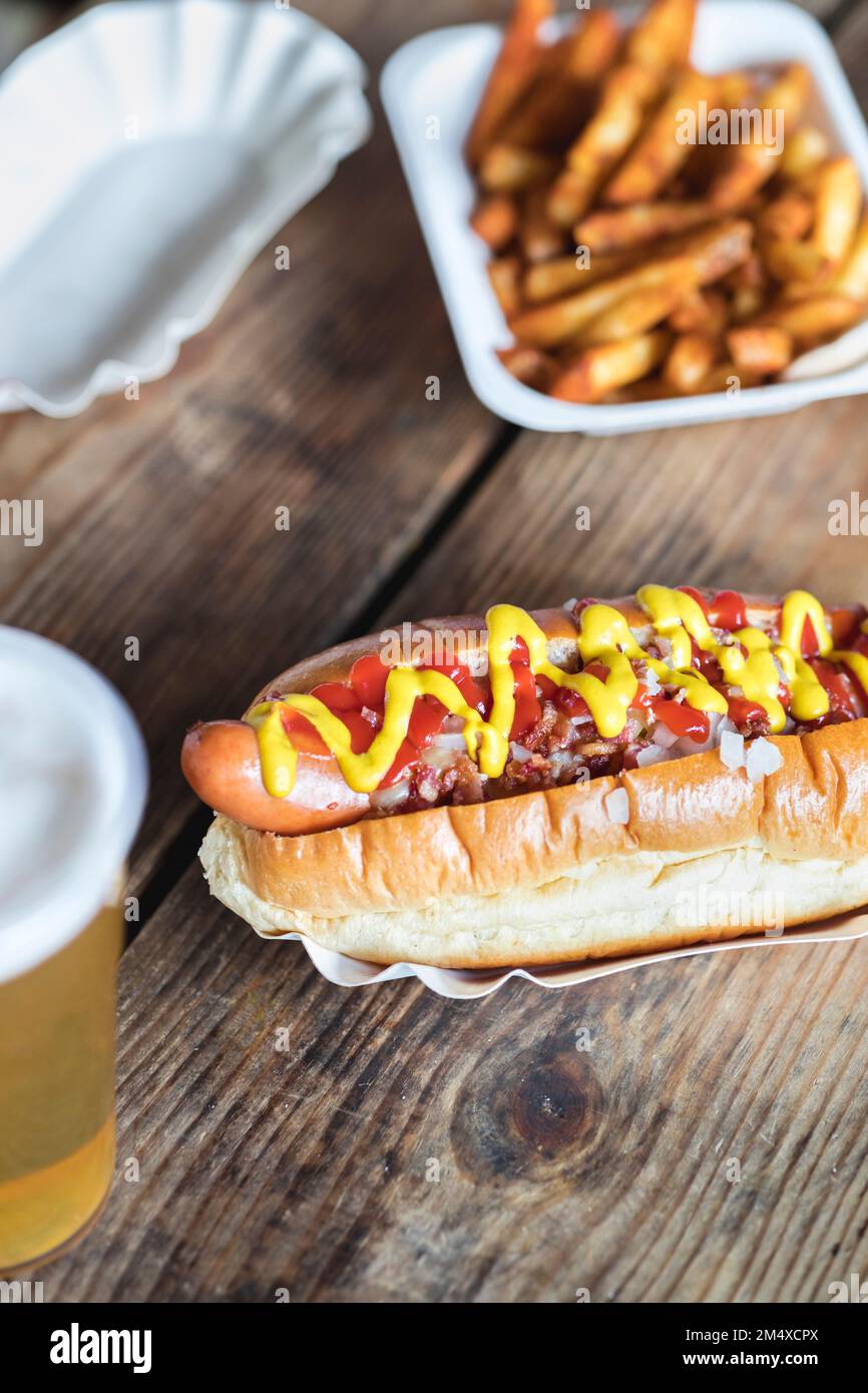 Moutarde et ketchup sur hot dog avec frites à la table Banque D'Images