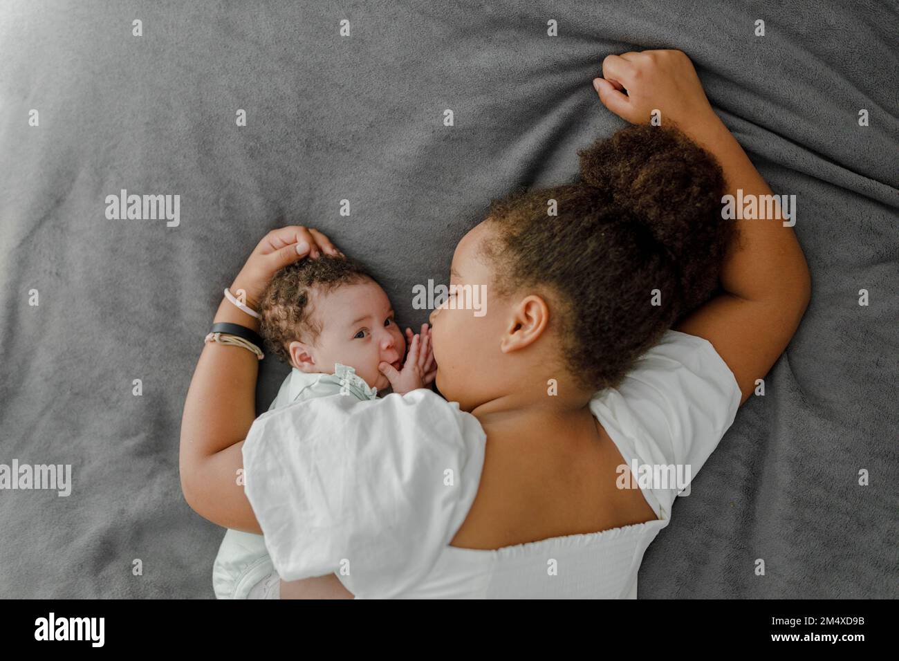Fille couchée sur le lit avec une petite sœur dans la chambre à la maison Banque D'Images