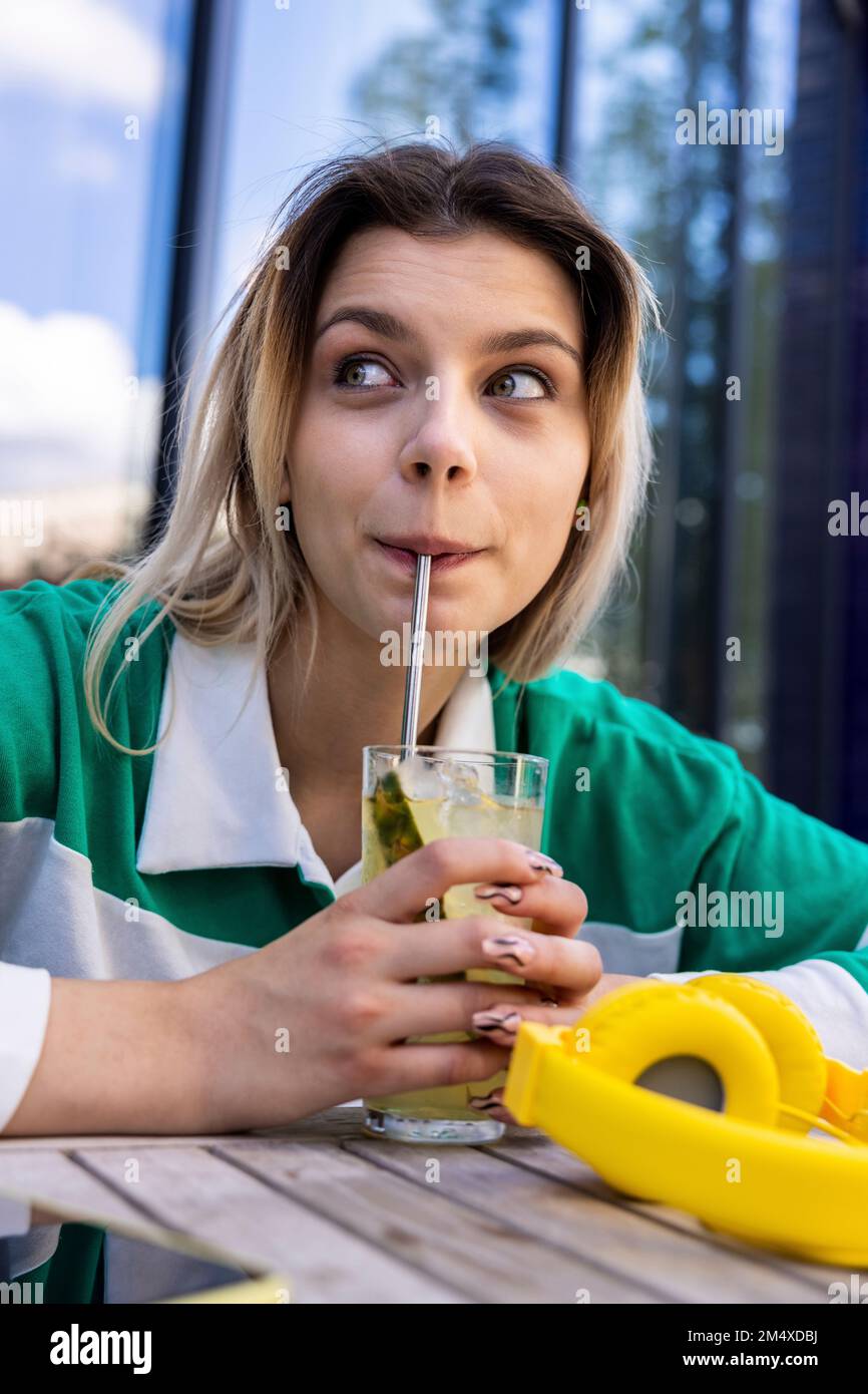 Jeune femme buvant du verre avec de la paille en acier inoxydable Banque D'Images