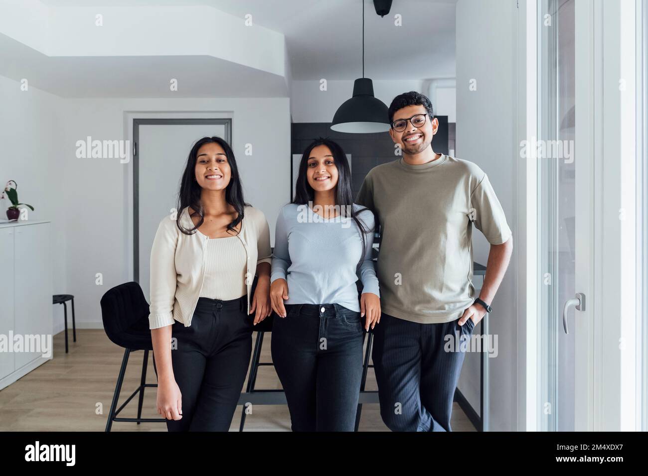 Homme souriant debout par des femmes dans le salon à la maison Banque D'Images