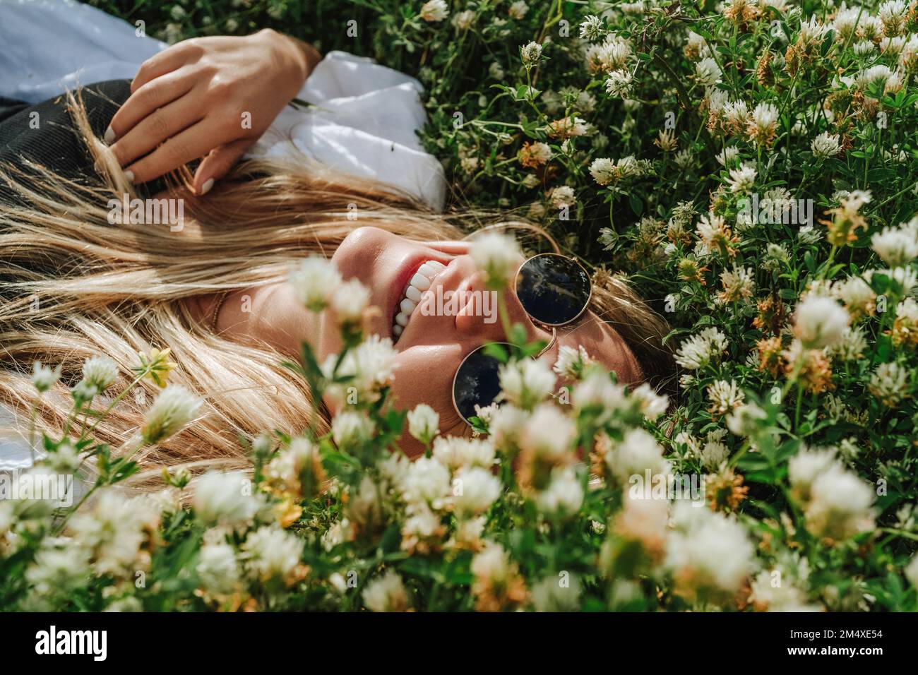 Femme heureuse couchée sur un pré non cultivé de fleurs sauvages Banque D'Images