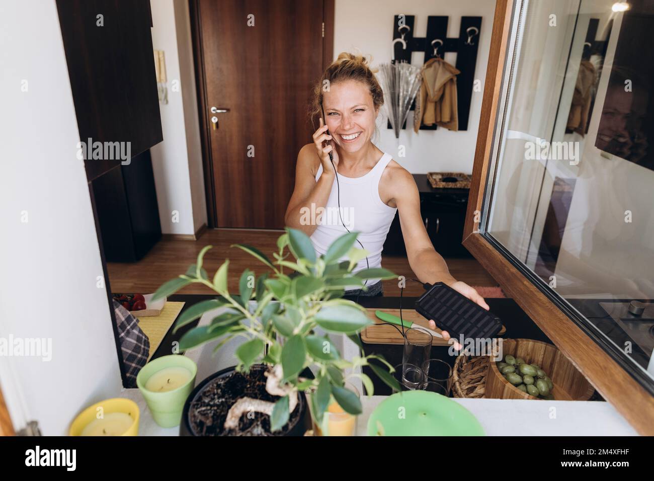 Bonne femme sur le téléphone chargé par la pile solaire dans la cuisine Banque D'Images