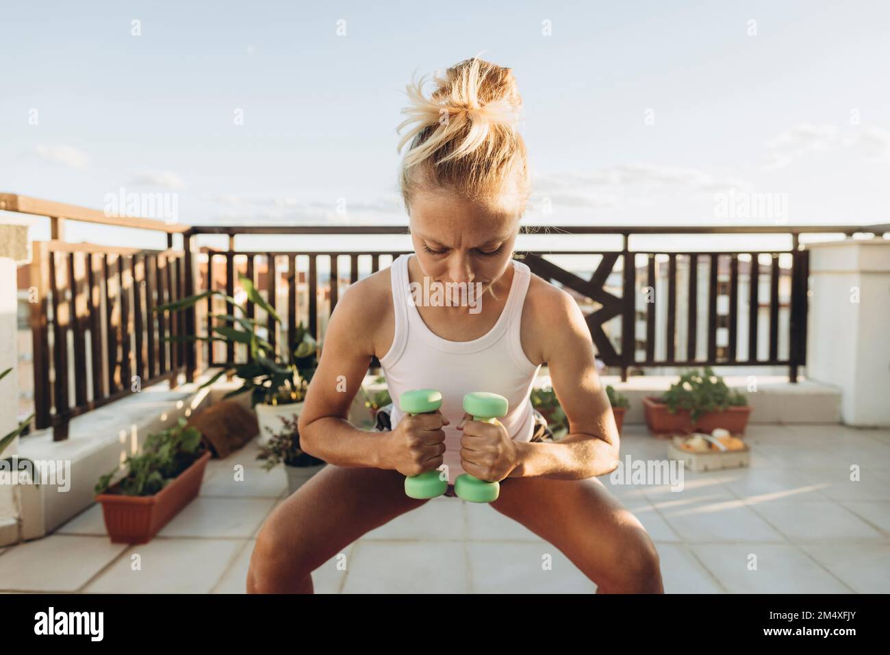 Femme faisant des exercices avec des haltères sur la terrasse du toit Banque D'Images