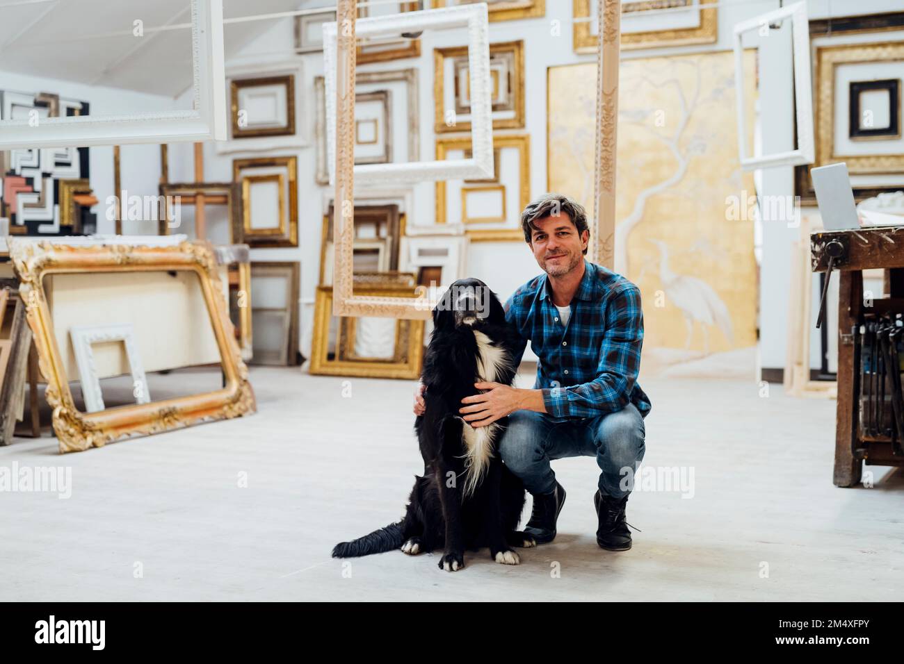 Homme souriant assis avec un chien dans un atelier Banque D'Images