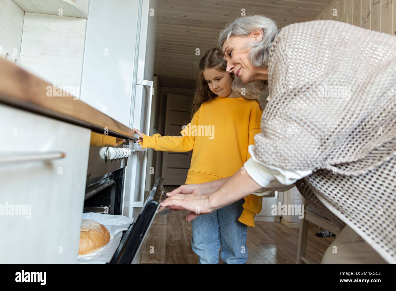 Grand-mère et petite-fille prenant du pain maison fraîchement cuit au four Banque D'Images