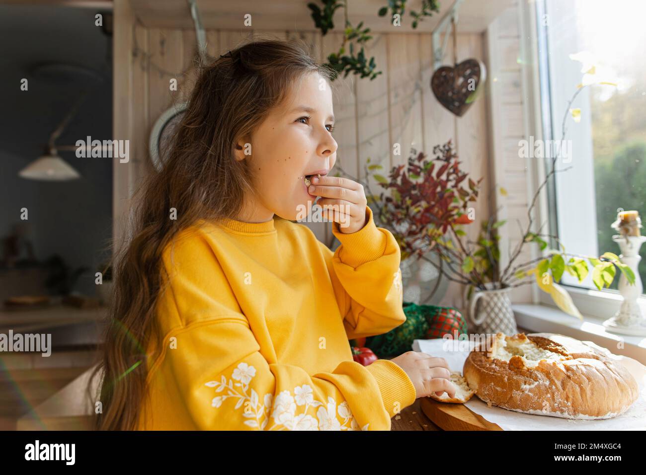 Une fille goûte du pain maison fraîchement cuit dans la cuisine Banque D'Images