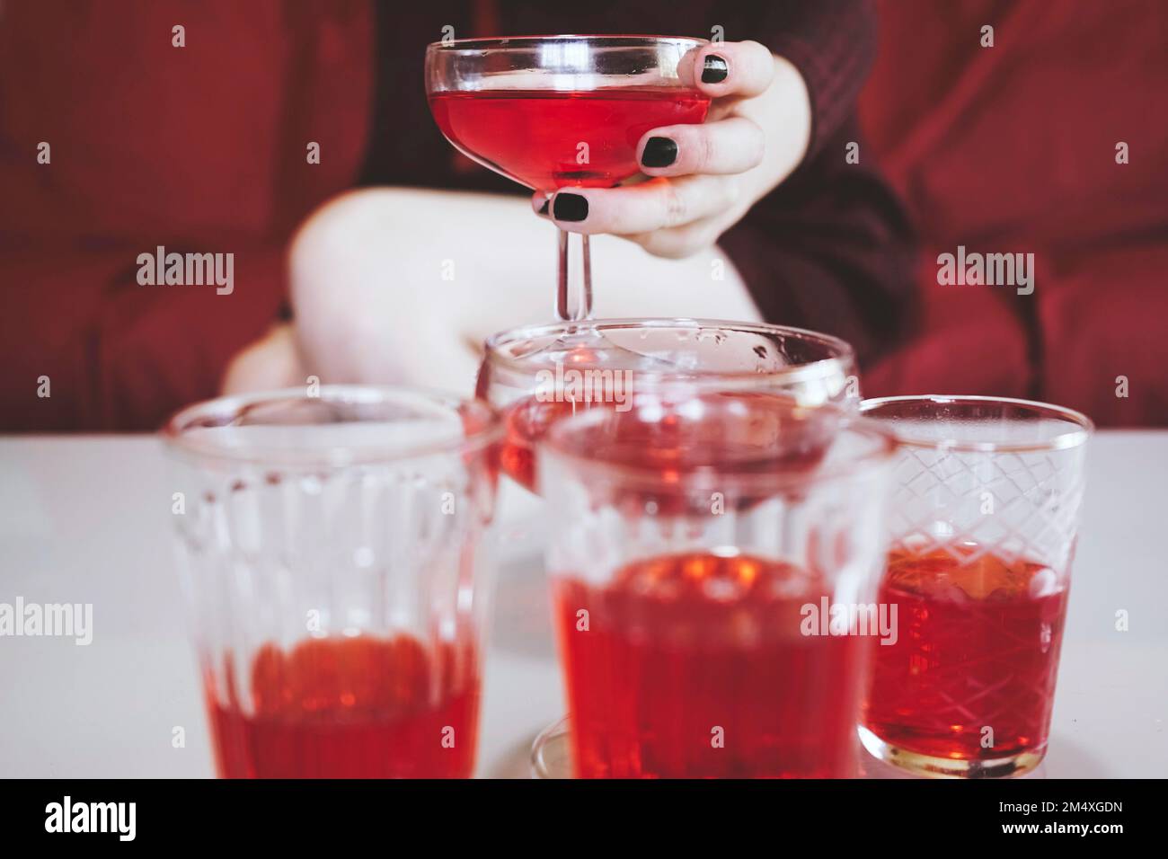 Main de femme tenant un coupé à champagne avec une boisson alcoolisée rouge Banque D'Images
