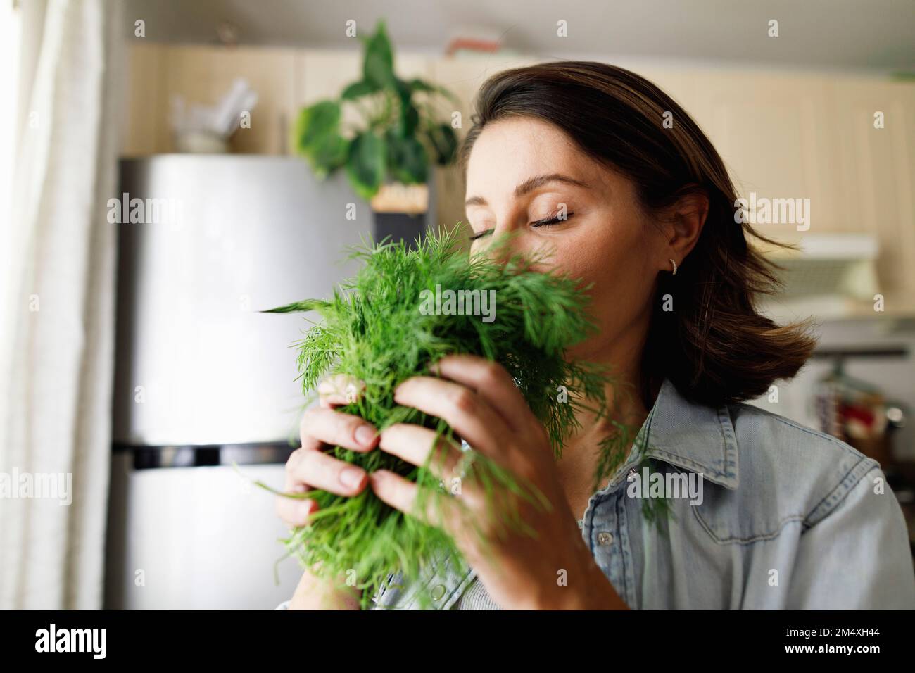 Femme mature qui sent des feuilles d'aneth à la maison Banque D'Images