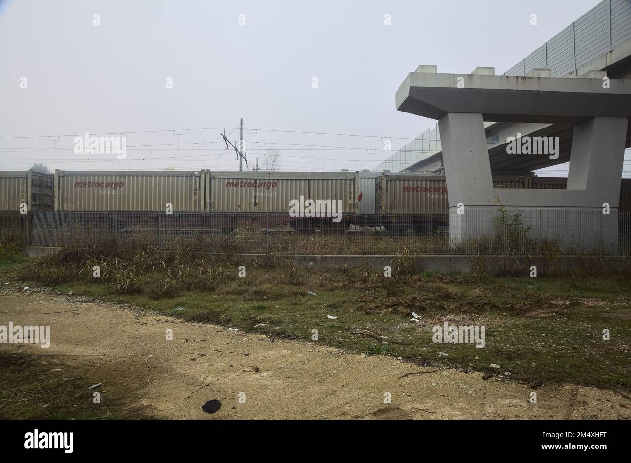 Chemin de fer avec des wagons de marchandises qui passe sous un viaduc un jour brumeux Banque D'Images