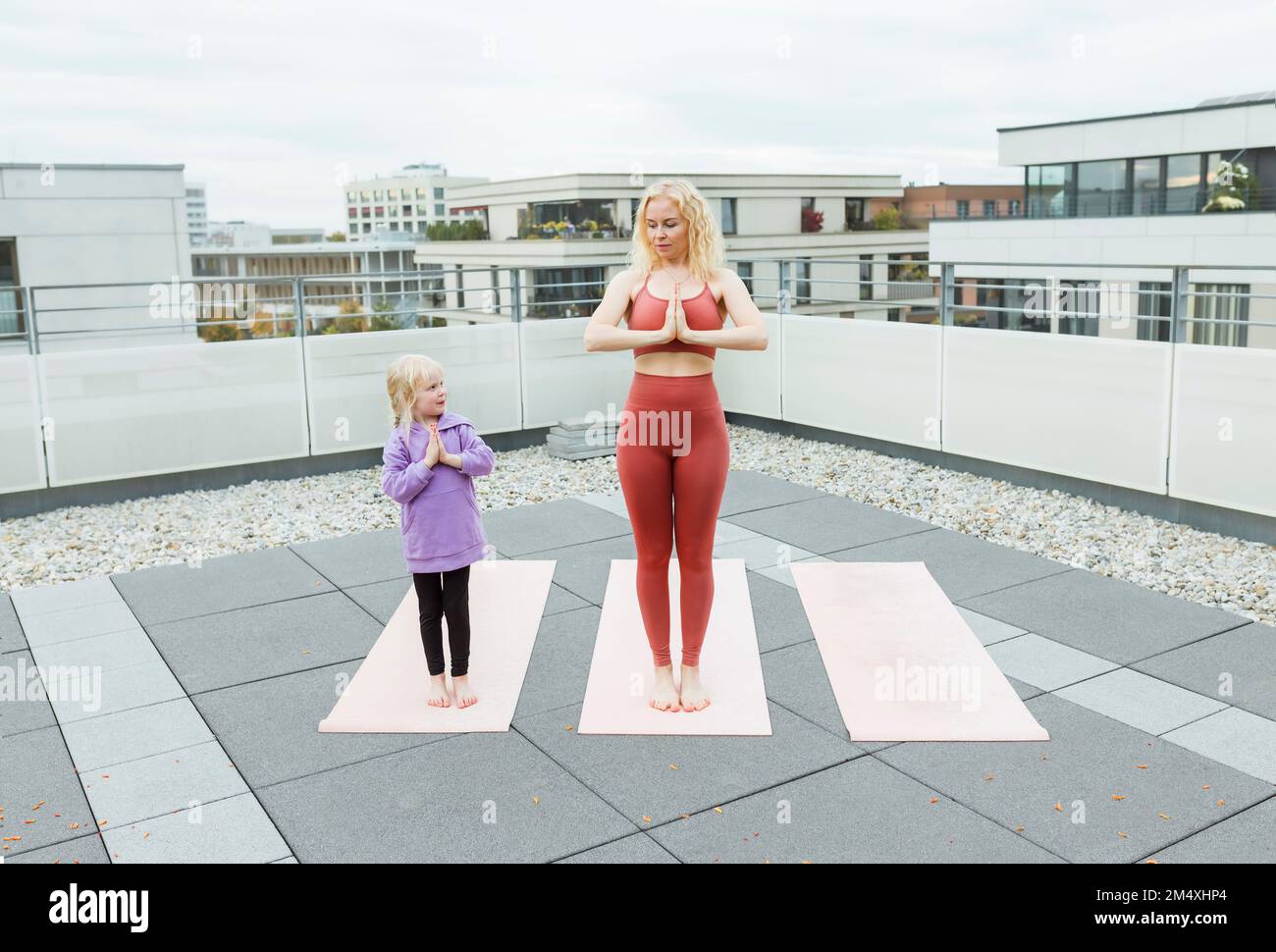 Jolie fille pratiquant le yoga avec une mère sur le toit Banque D'Images