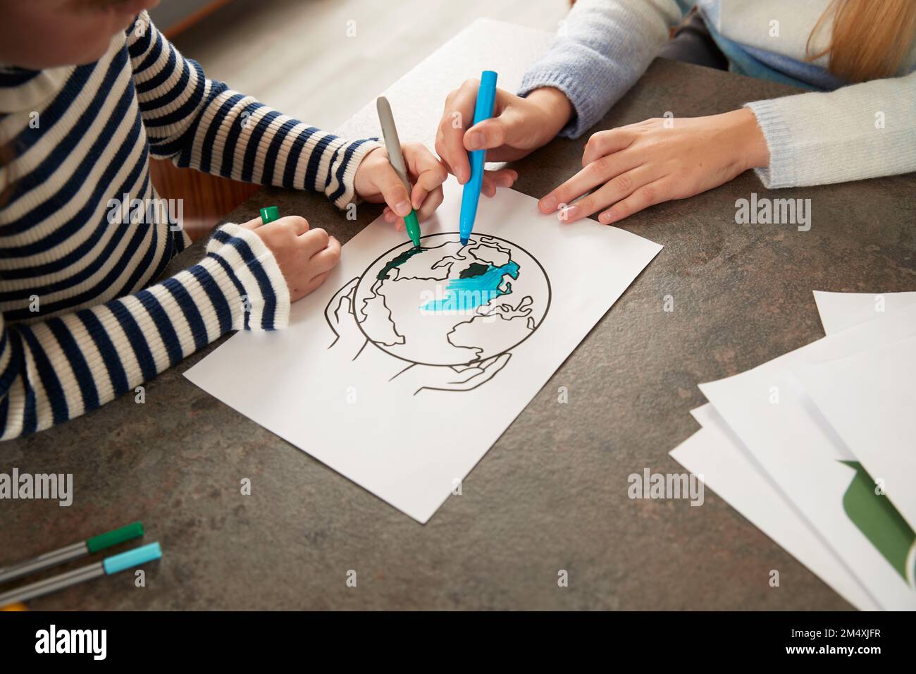 Mains de filles colorant la terre de la planète avec des stylos à la maison Banque D'Images