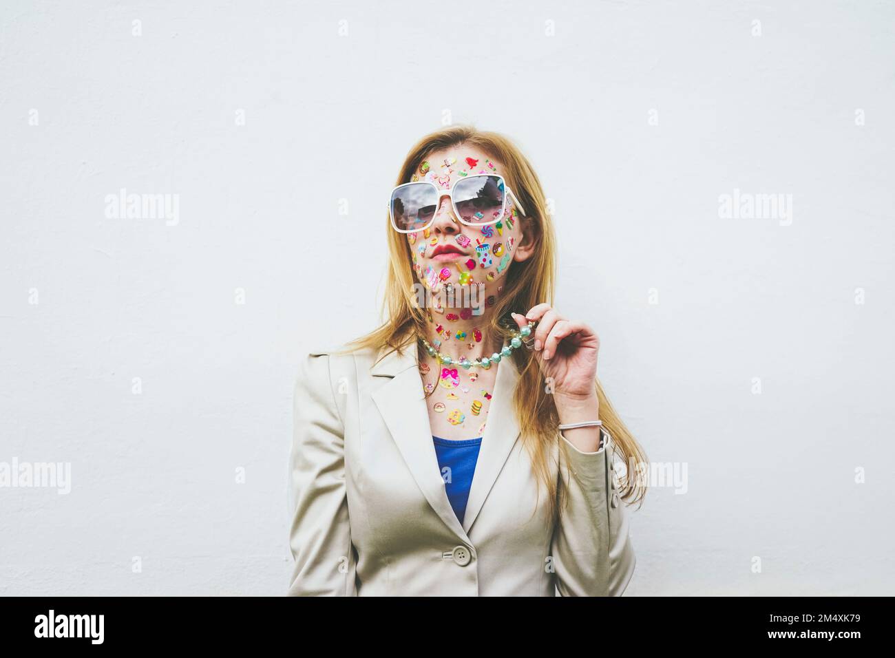 Femme avec des autocollants colorés sur le visage devant un fond blanc Banque D'Images