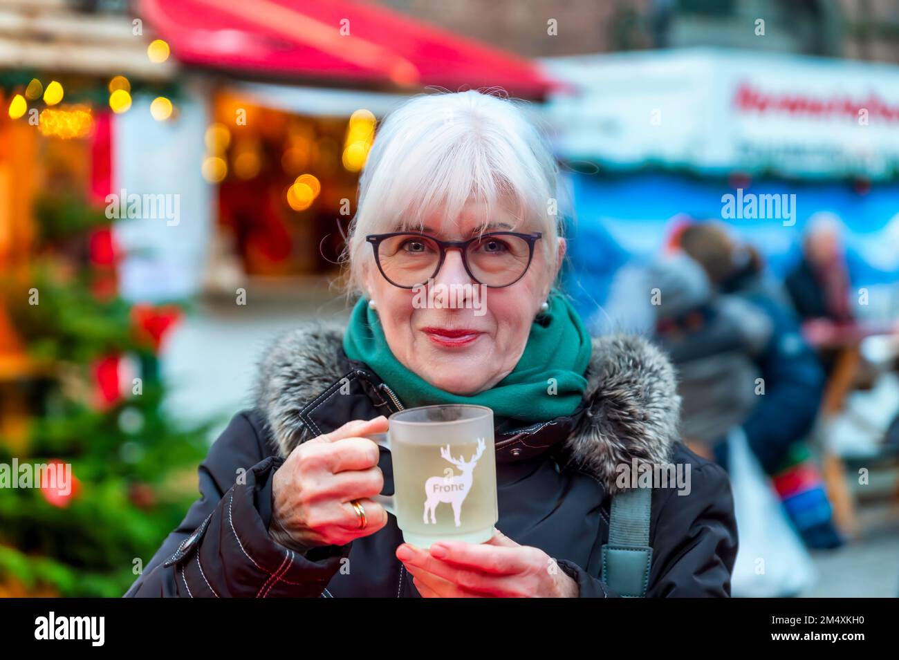 Femme aînée souriante avec une tasse de vin chaud au marché de Noël Banque D'Images