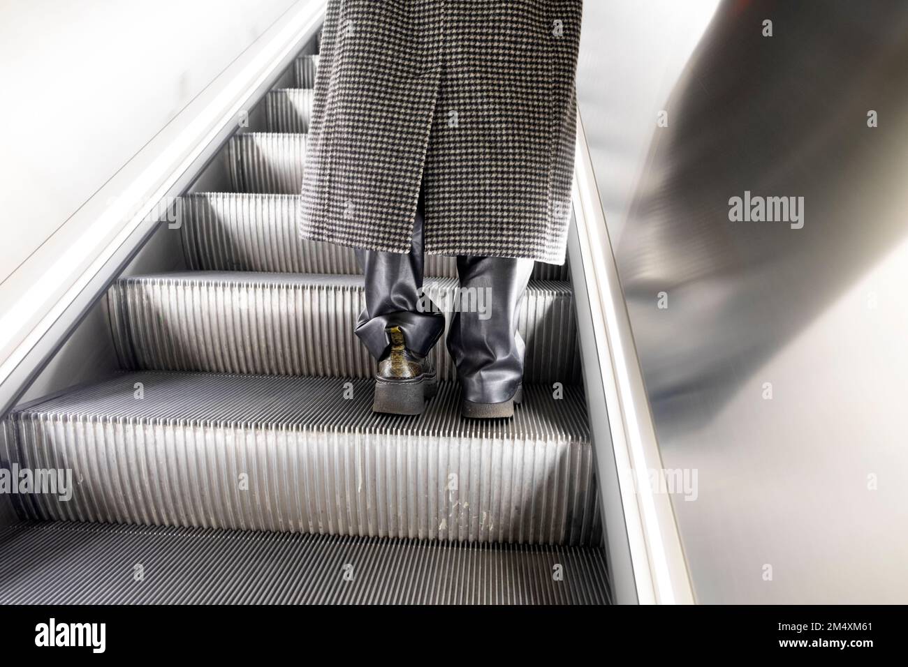 Vue arrière des pieds bottes en cuir et manteau d'hiver de femme sur l'escalier mécanique Elizabeth Line Farringdon station de métro Londres Angleterre Royaume-Uni KATHY DEWITT Banque D'Images