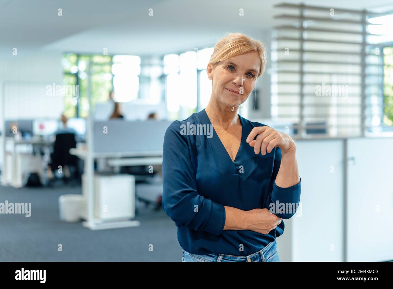Femme d'affaires souriante aux cheveux blonds sur le lieu de travail Banque D'Images