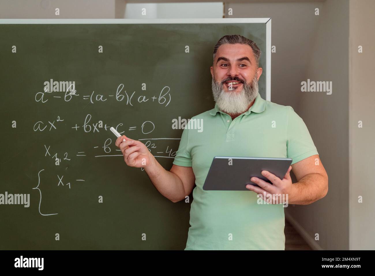 Professeur mature avec un PC tablette pour l'enseignement des mathématiques sur tableau de surveillance Banque D'Images