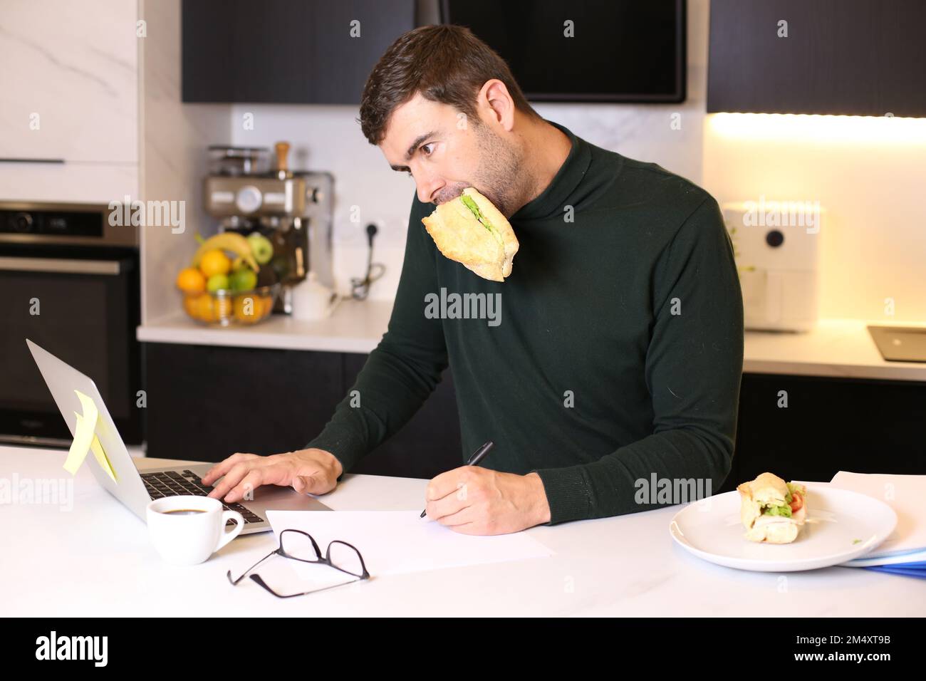 Homme occupé mangeant un sandwich pendant la conférence téléphonique Banque D'Images
