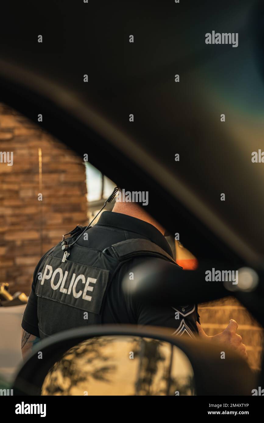 Image verticale de l'officier de police blanc de race blanche debout à l'extérieur du véhicule de la cdp, vu de l'intérieur de la voiture de patrouille. Affiche uniquement la copie de police sur ba Banque D'Images